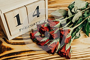 St. valentines day minimal concept on wooden background. Red roses and wooden caledar with 14 february on it