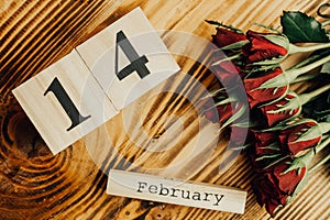 St. valentines day minimal concept on wooden background. Red roses and wooden caledar with 14 february on it