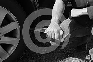 Stabbing a car tire with a long knife