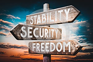 Stability, security, freedom - wooden signpost, roadsign with three arrows photo