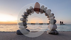 Stability stone arch with red stone at top in the morning on a beach. Wellness and nature concept. Balance concept.