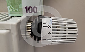 A stack of 100 euro banknotes on the thermostat temperature controller of a radiator battery