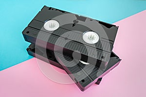 Stack of 3 VHS tapes on pink and blue background.