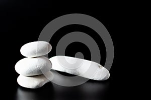 Stack of 3 white zen rocks piled up on a black background