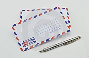 Stack of air mail envelopes and pen on white