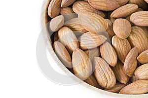 Stack of almonds in wooden bowl on white background isolated.