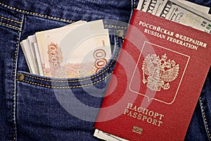 A stack of American hundred dollar bills in the international passport of Russia and Russian rubles in a pocket of blue jeans.