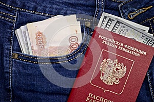 A stack of American hundred dollar bills in the international passport of Russia and Russian rubles in a pocket of blue jeans.