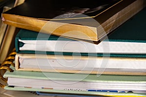 Stack of assorted hardback and paperback books or journals - some with bookmarks - closeup detail with selective focus