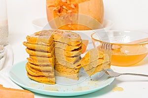 A stack of autumn pumpkin pancakes with Chia seeds and honey on a light background. delicious healthy vegetarian diet