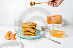 A stack of autumn pumpkin pancakes with Chia seeds and honey on a light background. delicious healthy vegetarian diet Breakfast.