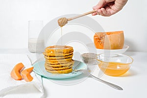 A stack of autumn pumpkin pancakes with Chia seeds and honey on a light background. delicious healthy vegetarian diet Breakfast.