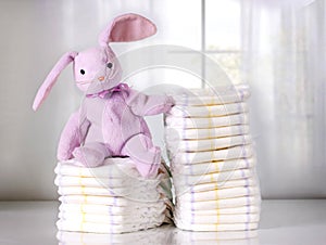 Toy bunny sitting on Stack of disposable diapers or nappies,Stack of diapers,pampers. photo
