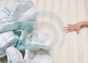 Stack of baby diapers on a white background and a baby hand, nappy