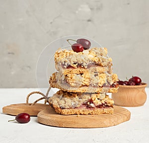 Stack of baked crumble pie with fruit filling and sprinkled with grated almonds on a wooden board