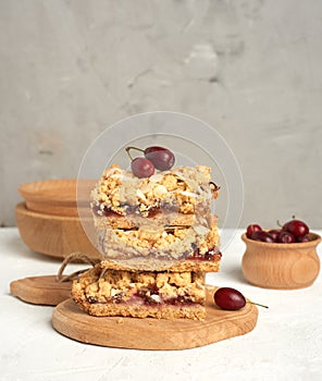 Stack of baked crumble pie with fruit filling and sprinkled with grated almonds on a wooden board