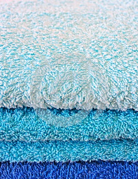 Stack of bath towels on light wooden background closeup.Pile of rainbow colored towels.Top view.