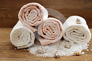 Stack of bath towels on wooden table. White and pink terry towels from cotton. Spa concept