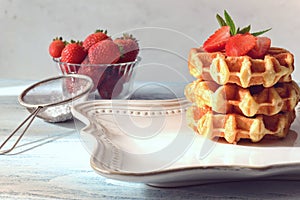 Stack of Belgian waffles with strawberries and mint leaves