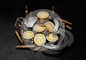 Stack of Bitcoin in open handcuffs and bullets. Bitcoin as a form of payment for illegal goods and services