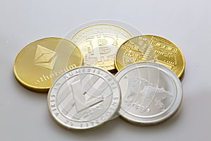 Stack of bitcoins and other crypto currencies on a white table