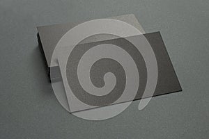 Stack of black blank textured business cards on dark paper background, us size 3.5 x 2 inches, as template for design presentation