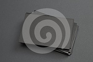 Stack of black blank textured business cards on dark paper background, us size 3.5 x 2 inches, as template for design presentation