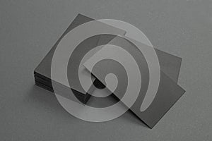 Stack of black blank textured business cards on dark paper background, us size 3.5 x 2 inches, as template for design presentation