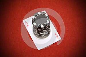 Stack of black poker chips on a red ace card