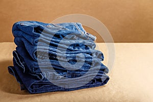 Stack of blue denim clothes. Pile folded blue denim pants in different shades of blue on brown craft background with