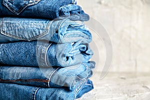 Stack of blue jeans on a gray background