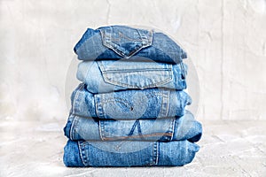 Stack of blue jeans on a gray background