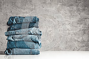 Stack of blue jeans on a gray background