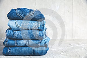 Stack of blue jeans on a gray background