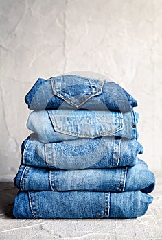 Stack of blue jeans on a gray background