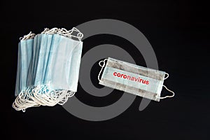 Stack of blue medical face masks isolated on black background with copy space, close-up. One mask separate. Protection against