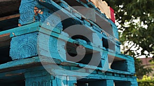 stack of blue palettes skids on top of one another with wood colored one on top-