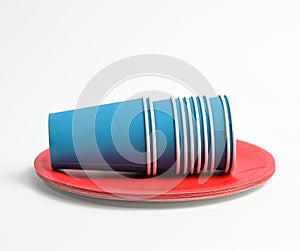 Stack of blue paper cups and red round plates on a white background
