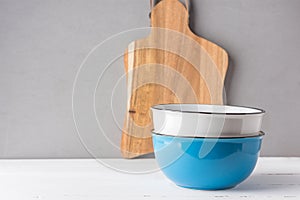 Stack of blue and white ceramic bowls wood cutting board on table gray wall background. Cooking baking cookware breakfast