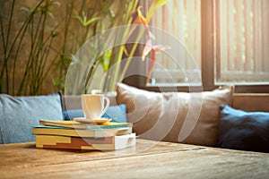 Stack of book with coffee cup on top on wooden table