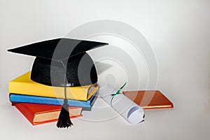 Stack of book and graduation cap on white