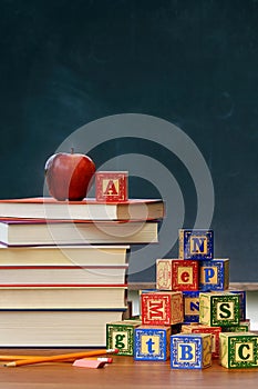 Stack of books with apple and wooden blocks