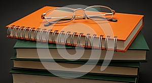 Stack of Books with Eyeglasses on Top Against a Dark Background reading education