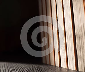 Stack of books on black table and light from sun