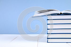 A stack of books on a blue background. One hidden book on top of the pile.