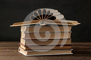 A stack of books on a brown wooden table and on a black background. Old books. Education. school. study