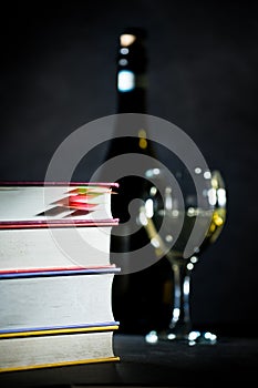 Stack of books with glass and bottle of white wine
