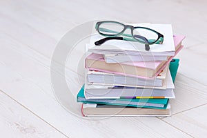 Stack of books with glasses on top. Concept cause of farsightedness, myopia photo