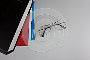 A stack of books and glasses on a white background.