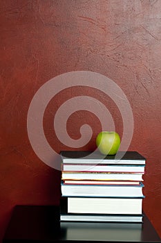 A stack of books with a green apple